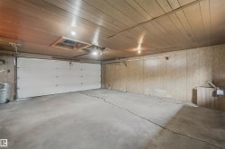 Attached garage featuring a concrete floor, wood-finish paneling, and overhead lighting - 