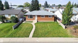 Pitched roof, light brown siding, white front door, concrete walkway, and manicured front lawn - 
