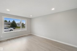 Spacious room featuring a large window, recessed lighting, light-toned walls, and wood-finish flooring - 