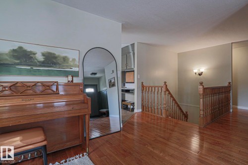 Wood-finish flooring throughout, solid wood stair railing, and a wall-mounted light fixture - 2 Hillview Crescent, Sherwood Park, AB 