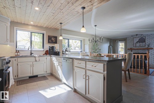 Kitchen featuring wood-finish plank ceiling, recessed lighting, white cabinetry, a center island with a dark countertop, and a white subway tile backsplash - 2 Hillview Crescent, Sherwood Park, AB 