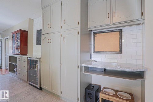 Built-in cabinetry with ample storage, integrated beverage cooler, white subway tile backsplash, and light-colored countertops - 2 Hillview Crescent, Sherwood Park, AB 