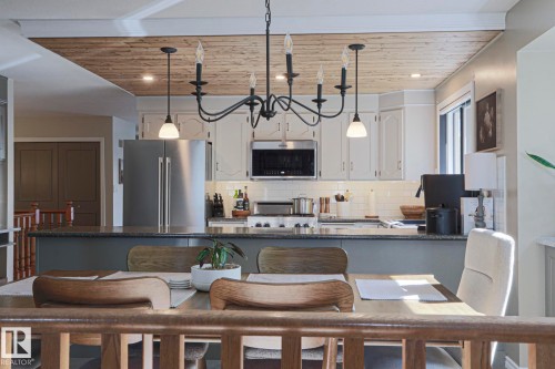 Kitchen featuring shaker-style cabinetry, stainless steel appliances, a subway tile backsplash, and a wood-paneled ceiling - 2 Hillview Crescent, Sherwood Park, AB 
