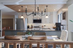 Kitchen featuring shaker-style cabinetry, stainless steel appliances, a subway tile backsplash, and a wood-paneled ceiling - 