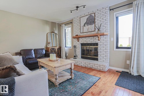 Brick fireplace with a wood mantle, wood-finish flooring, and recessed lighting - 2 Hillview Crescent, Sherwood Park, AB 