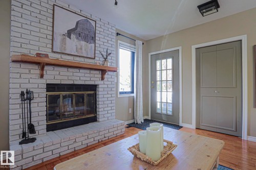 White-painted brick fireplace with a wood mantle and hearth, glass-paned door, and wood-finish flooring - 2 Hillview Crescent, Sherwood Park, AB 