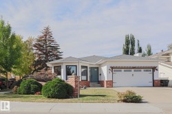 White siding exterior with brick accents, black-framed windows, an attached two-car garage, and a landscaped front yard with mature shrubbery - 