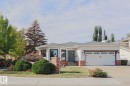 White siding exterior with brick accents, black-framed windows, an attached two-car garage, and a landscaped front yard with mature shrubbery - 2 Hillview Crescent, Sherwood Park, AB 
