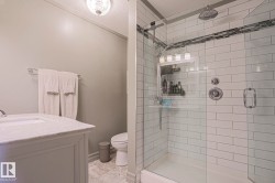 Walk-in shower with subway tile surround, integrated mosaic tile accent, and glass enclosure - 