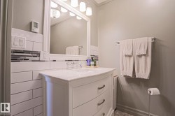 White vanity with an integrated sink, polished chrome faucet, and subway tile backsplash with an accent strip - 