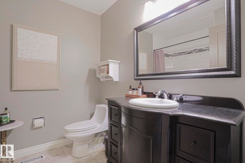 Vanity with a dark countertop and undermount sink, framed mirror, and light gray wall paint - 2 Hillview Crescent, Sherwood Park, AB 