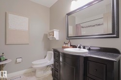 Vanity with a dark countertop and undermount sink, framed mirror, and light gray wall paint - 