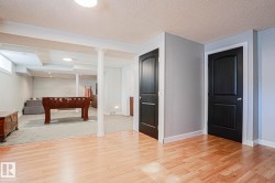 Wood-finish flooring, light gray wall paint, white baseboards, and black panel doors - 