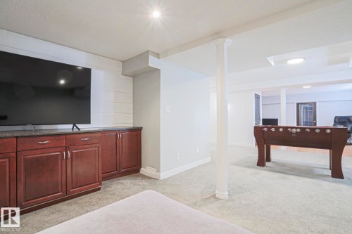 Recessed lighting, wood-finish cabinetry, built-in media console with dark countertop, carpet flooring, and white shiplap accent wall - 2 Hillview Crescent, Sherwood Park, AB 
