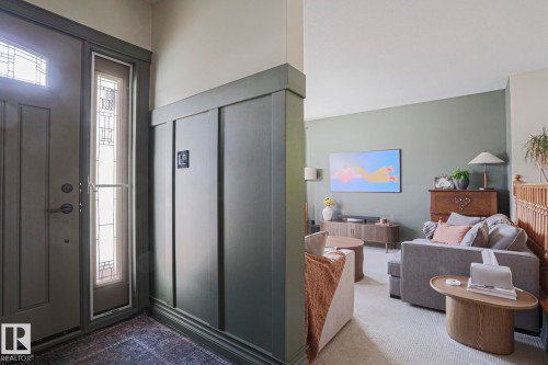 Entryway featuring a decorative front door with transom and sidelight, board and batten wall paneling, and a warm color palette - 2 Hillview Crescent, Sherwood Park, AB 