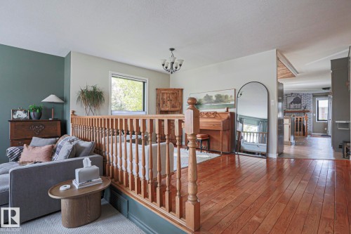 Hardwood flooring, painted accent wall, built-in baluster railing, contemporary light fixture, and window with natural light - 2 Hillview Crescent, Sherwood Park, AB 
