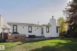 Expansive backyard featuring a manicured lawn, a multi-level deck, and a white pergola - 