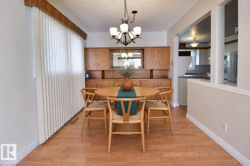 Wood-finish flooring throughout, built-in wooden cabinetry, recessed lighting, and a contemporary chandelier - 4420 117A Street Nw, Edmonton, AB 