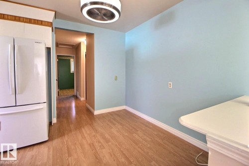 Wood-finish flooring throughout, complemented by a contemporary flush-mount ceiling light fixture - 4420 117A Street Nw, Edmonton, AB 
