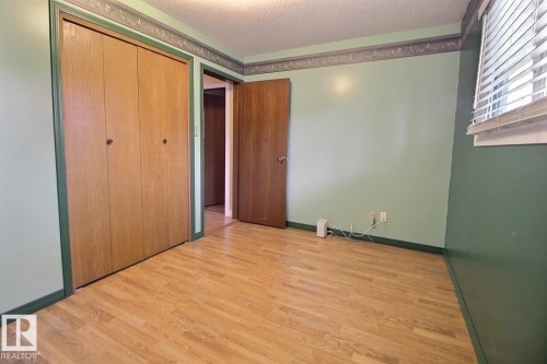 Wood-finish flooring with a multi-panel bifold closet - 4420 117A Street Nw, Edmonton, AB 
