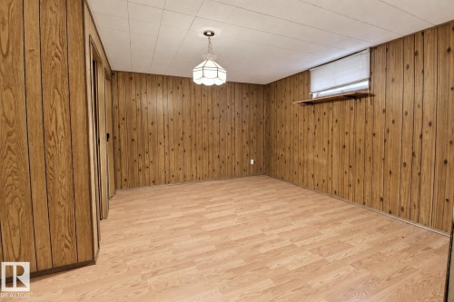 Wood-finish wall paneling throughout, patterned wood-finish flooring, and a white grid ceiling - 4420 117A Street Nw, Edmonton, AB 