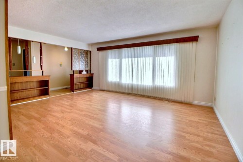 Wood-finish flooring throughout, large window with vertical blinds, and built-in shelving - 4420 117A Street Nw, Edmonton, AB 