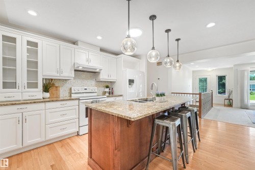 Modern kitchen featuring white cabinetry, stone countertops, a tiled backsplash, and recessed lighting - 8212 148 Street Nw, Edmonton, AB 