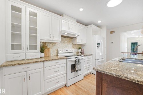 White cabinetry with glass-front uppers, light-toned countertops, and a tile backsplash - 8212 148 Street Nw, Edmonton, AB 