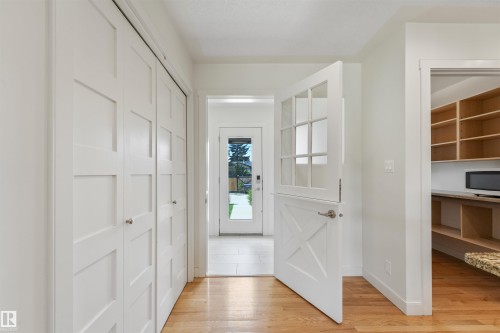 Light wood-finish flooring, white paneled doors, sliding closet doors, full-light back door, and a walk-in pantry with built-in shelving - 8212 148 Street Nw, Edmonton, AB 