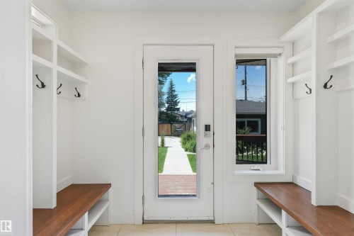 Entryway featuring built-in white cabinetry, integrated wood-finish benches, and dark metal coat hooks - 8212 148 Street Nw, Edmonton, AB 