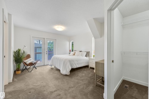 White walls, carpet flooring, a built-in closet with wire shelving, and double French patio doors - 8212 148 Street Nw, Edmonton, AB 