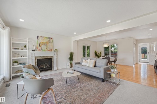 Living area featuring a fireplace with a stone surround, recessed lighting, and mixed flooring - 8212 148 Street Nw, Edmonton, AB 