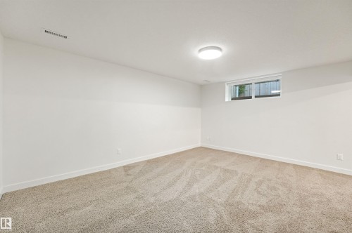 Neutral-toned carpeting, white painted walls, and a single window with privacy fencing - 8212 148 Street Nw, Edmonton, AB 