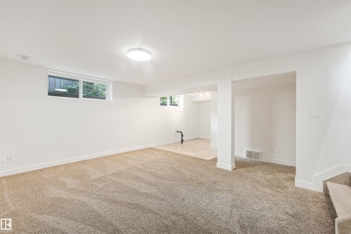 Spacious room featuring neutral carpeting, recessed lighting, and multiple windows - 8212 148 Street Nw, Edmonton, AB 