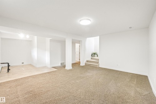 Open lower-level space featuring neutral carpeting, recessed lighting, and a partial tile-finish floor - 8212 148 Street Nw, Edmonton, AB 