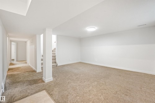 Expansive carpeted area with neutral wall finishes, recessed lighting, and a visible staircase - 8212 148 Street Nw, Edmonton, AB 