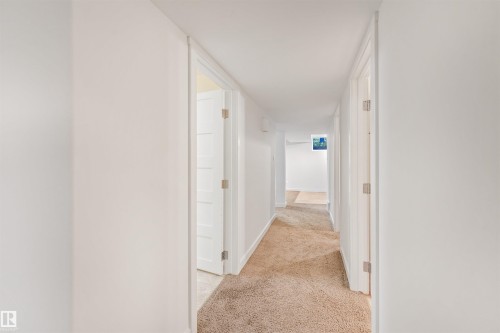Carpeted hallway with white walls and trim, featuring white interior doors - 8212 148 Street Nw, Edmonton, AB 