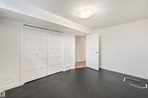 White paneled bifold closet doors, interior paneled door, flush-mount ceiling light fixture, and dark flooring - 8212 148 Street Nw, Edmonton, AB 