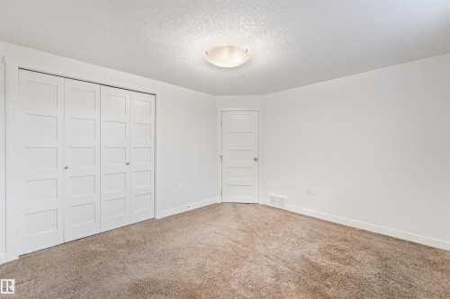 Neutral-toned carpeting, white walls, and a ceiling-mounted light fixture - 8212 148 Street Nw, Edmonton, AB 