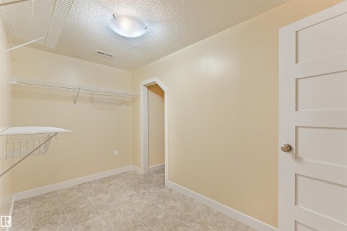Tile flooring, wire shelving, flush mount ceiling light, paneled interior door, and neutral wall paint - 8212 148 Street Nw, Edmonton, AB 