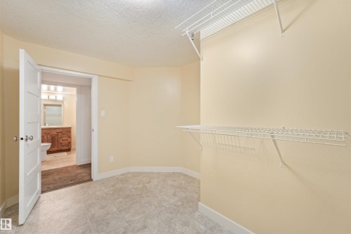 Spacious room featuring tile flooring, neutral wall tones, and built-in wire shelving - 8212 148 Street Nw, Edmonton, AB 