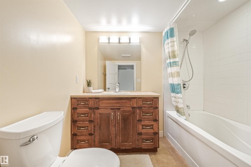 Wood-finish vanity with an integrated sink, broad mirror, and overhead light bar - 8212 148 Street Nw, Edmonton, AB 