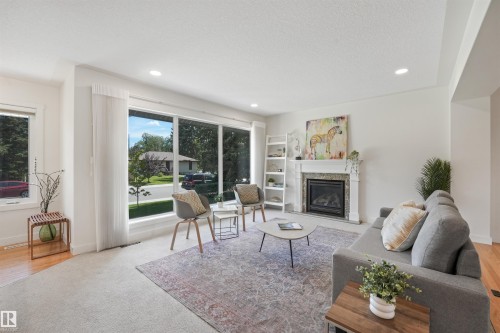 Expansive windows, recessed lighting, a fireplace with a decorative mantel, and wood-finish flooring - 8212 148 Street Nw, Edmonton, AB 
