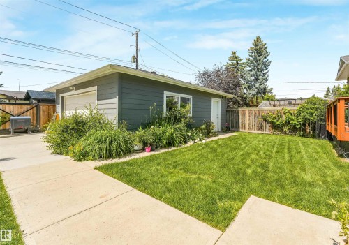 Detached garage with horizontal siding, a side entry door, and a dedicated concrete pathway - 8212 148 Street Nw, Edmonton, AB 