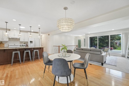 Light wood-finish flooring throughout, complemented by a kitchen island with seating - 8212 148 Street Nw, Edmonton, AB 