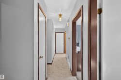 Hallway with light gray painted walls, a flush-mount ceiling light fixture, and wood-finish door frames - 