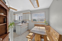 Kitchen featuring light gray cabinetry with wood trim, white countertops, tile flooring, and a built-in wooden dining nook - 