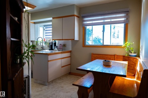 Kitchen featuring white cabinetry with wood-finish trim, stainless steel sink, and light-colored countertops - 11119 137 Avenue Nw, Edmonton, AB 