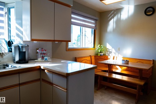 Kitchen featuring L-shaped countertop, stainless steel sink, upper and lower cabinetry, and tiled backsplash - 11119 137 Avenue Nw, Edmonton, AB 