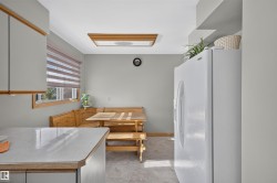 Built-in corner bench seating, window with layered shades, overhead lighting fixture, and white refrigerator - 